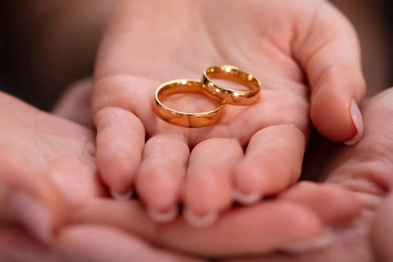 Hands holding out wedding rings