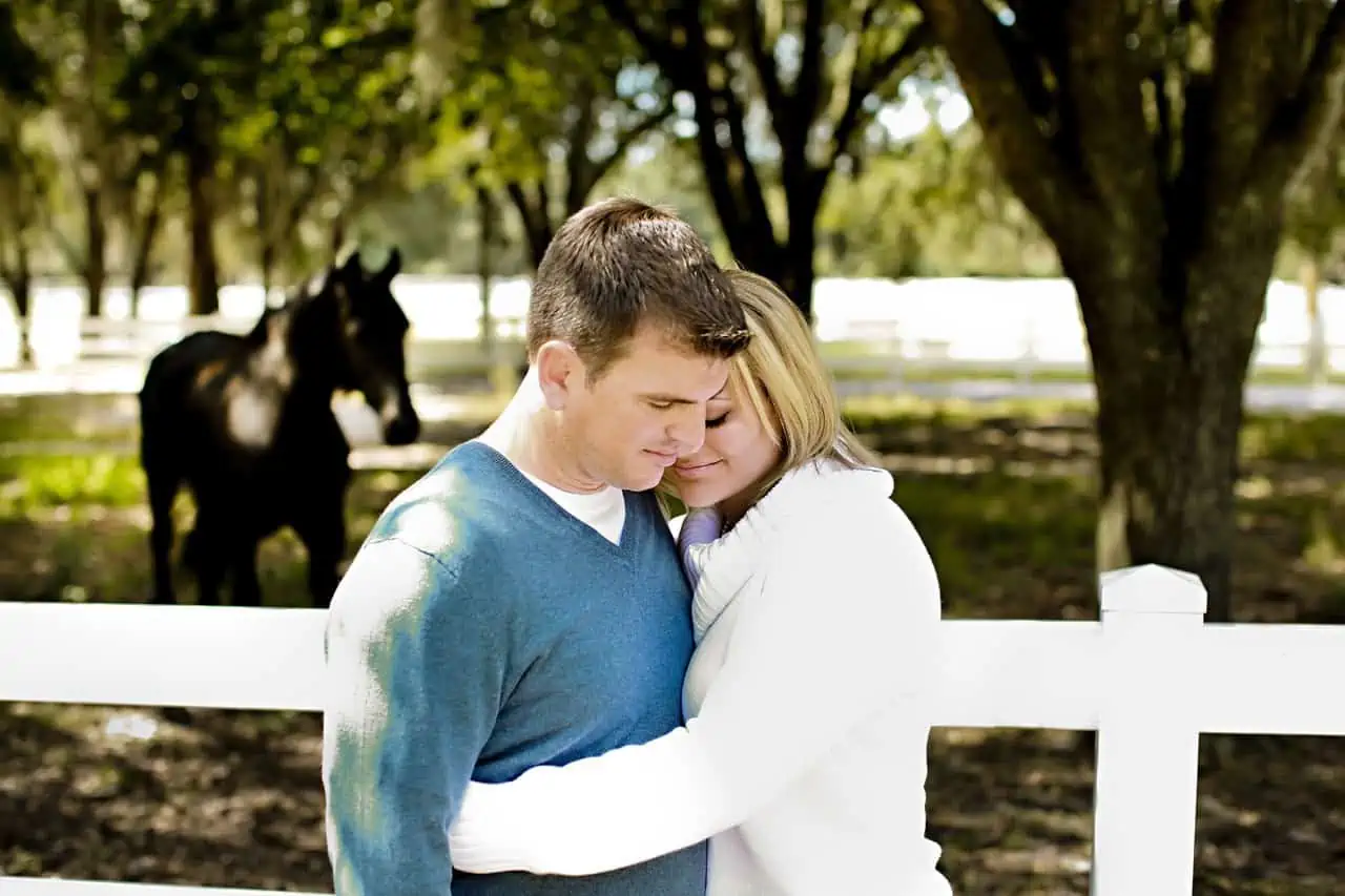 A man and a woman embracing in front of a white fence