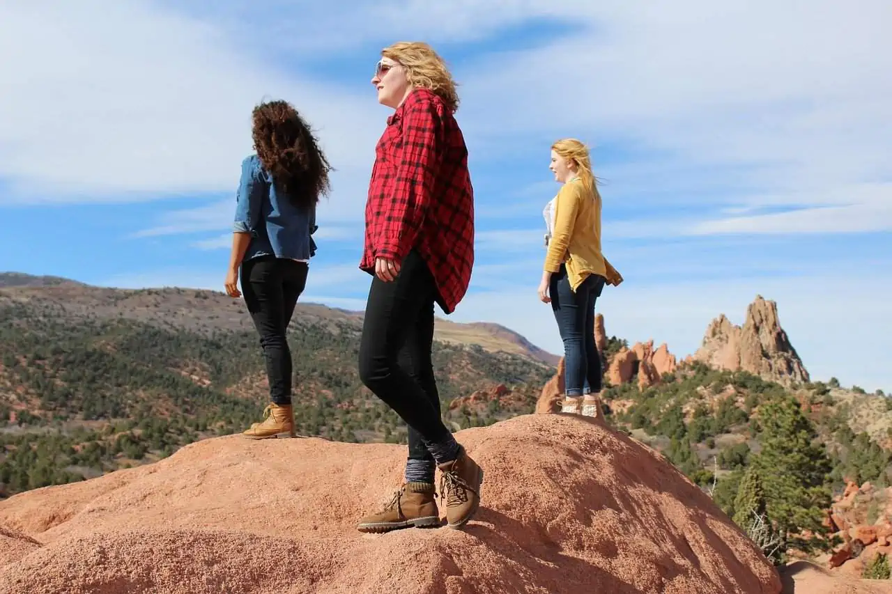 Three women standing on top of a large rock
