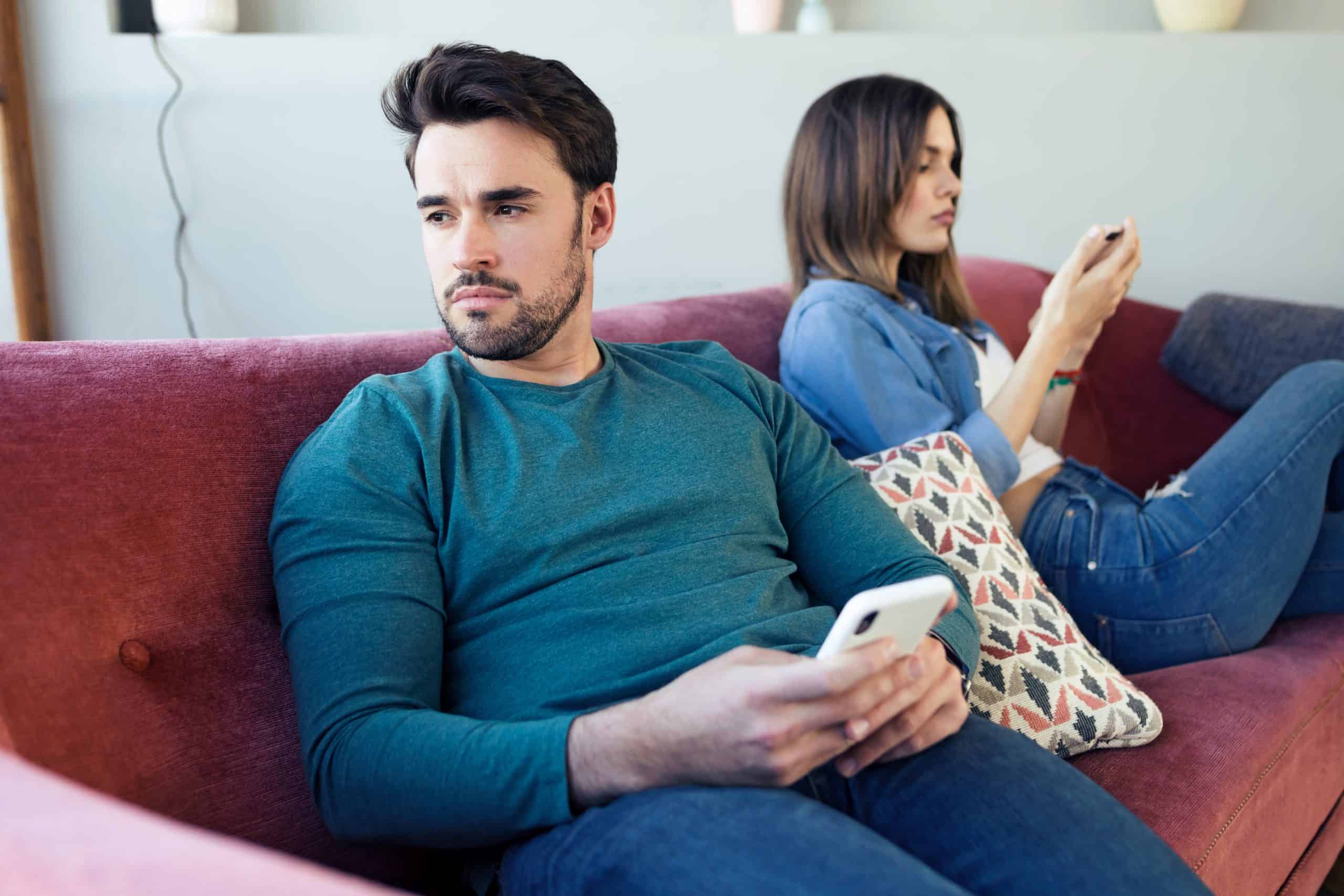 A man and a woman sitting on a red couch