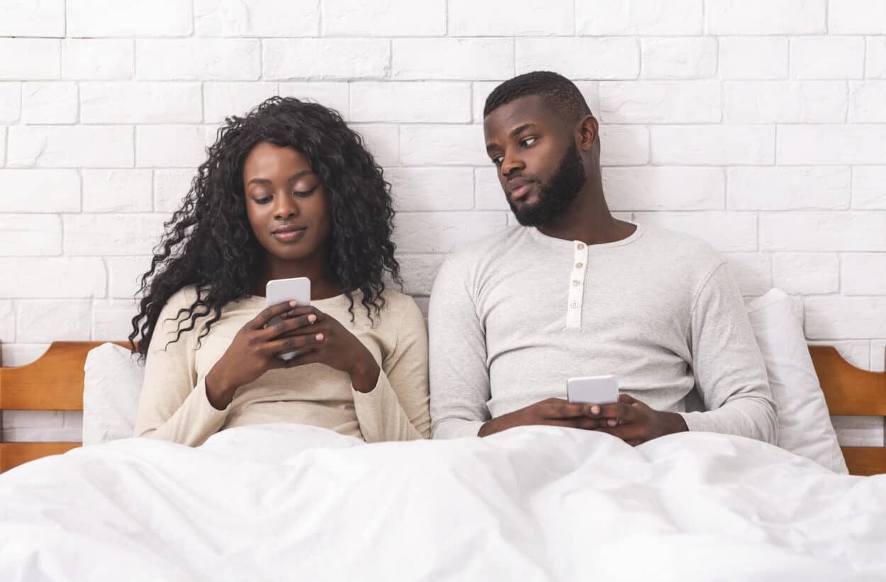 Man peeking over his wife's cellphone