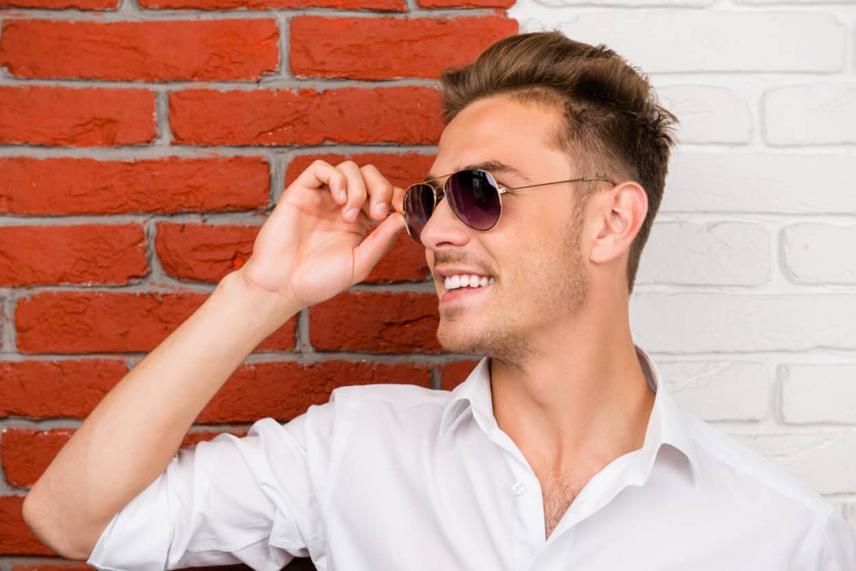 Man smiling holding his glasses