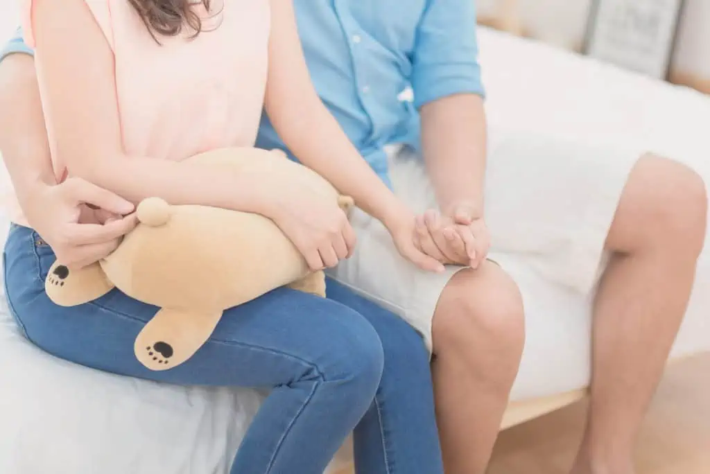 Couple Holding Hands Sitting On The Bed