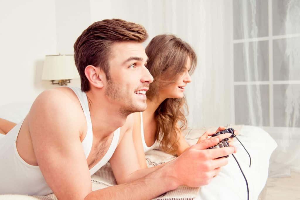 Couple playing console games in bed