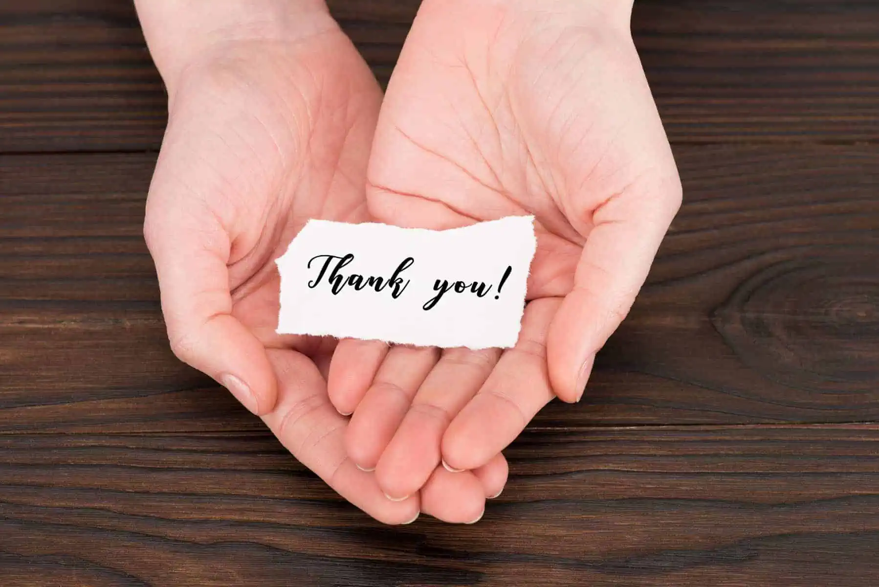 Two hands holding a piece of paper that says thank you