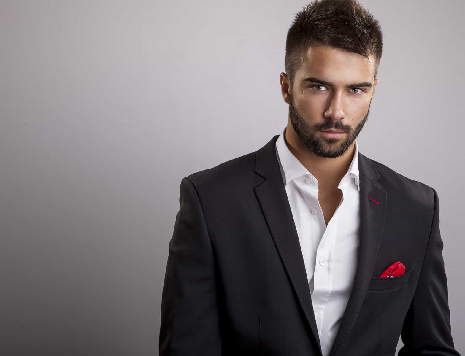 A man in a black suit with a red rose on his lapel