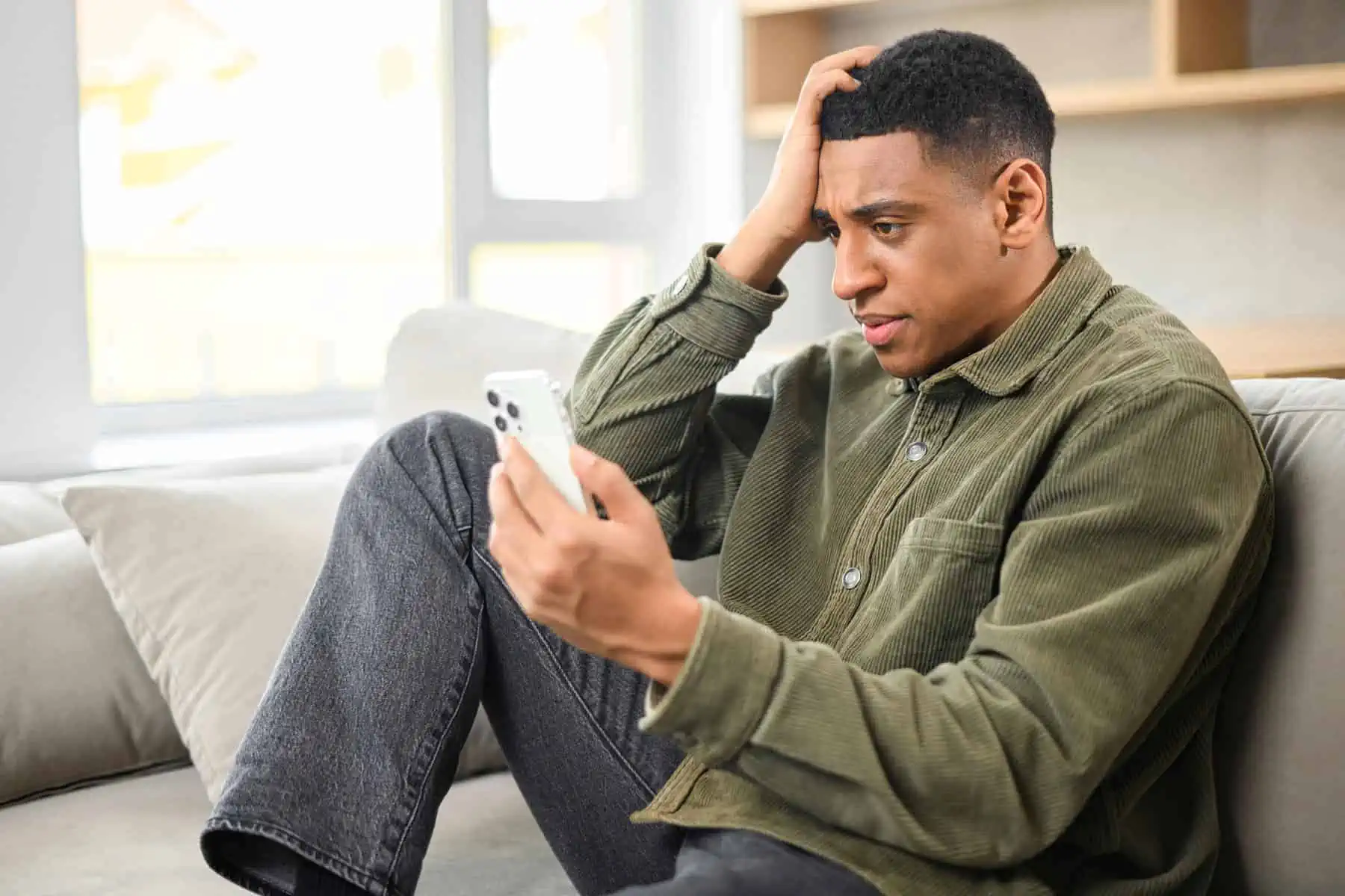 A man sitting on a couch looking at a cell phone