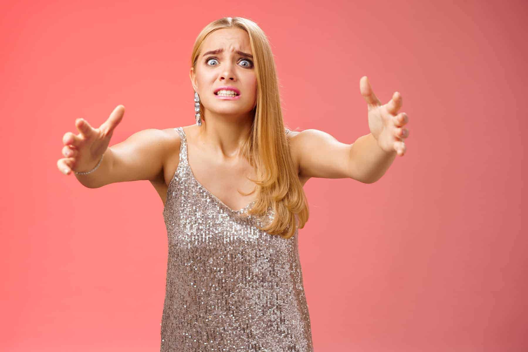 A woman in a silver dress making a face with her hands