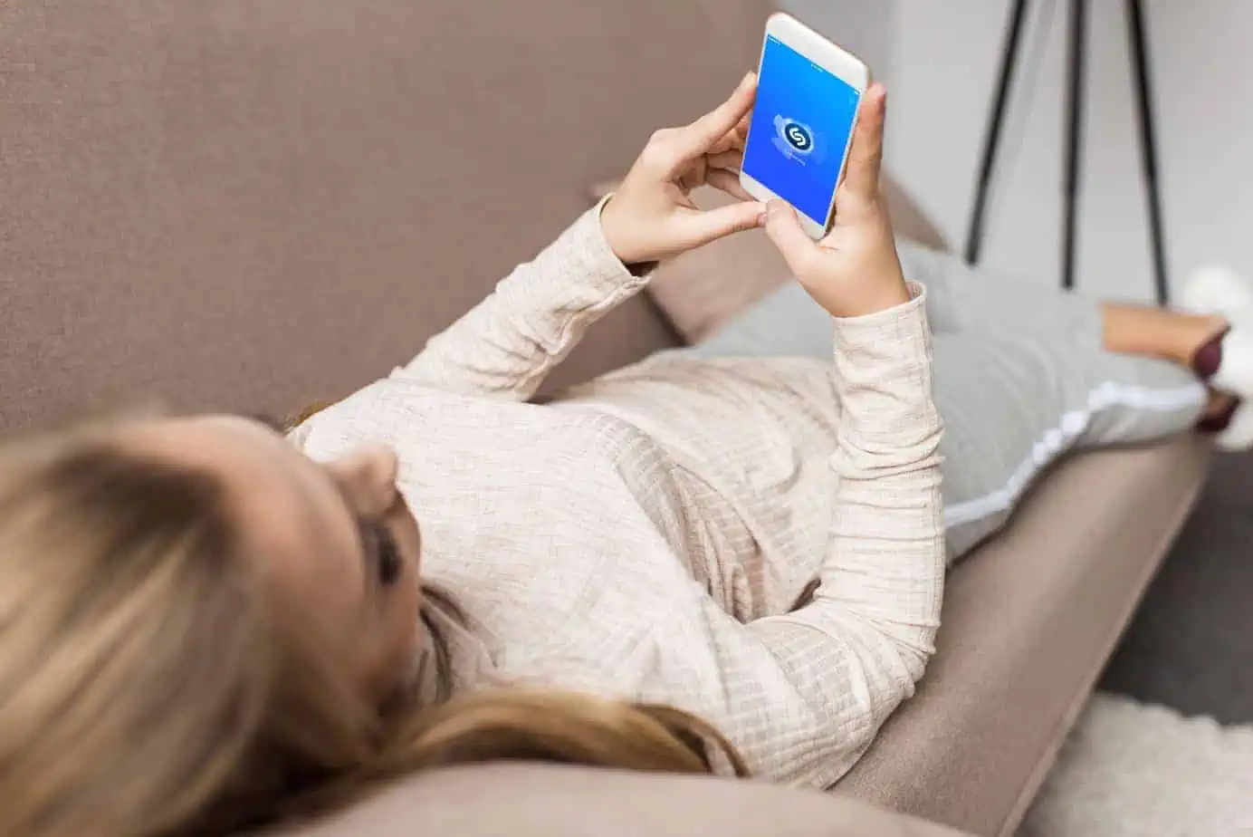 A woman laying on a couch holding a smart phone