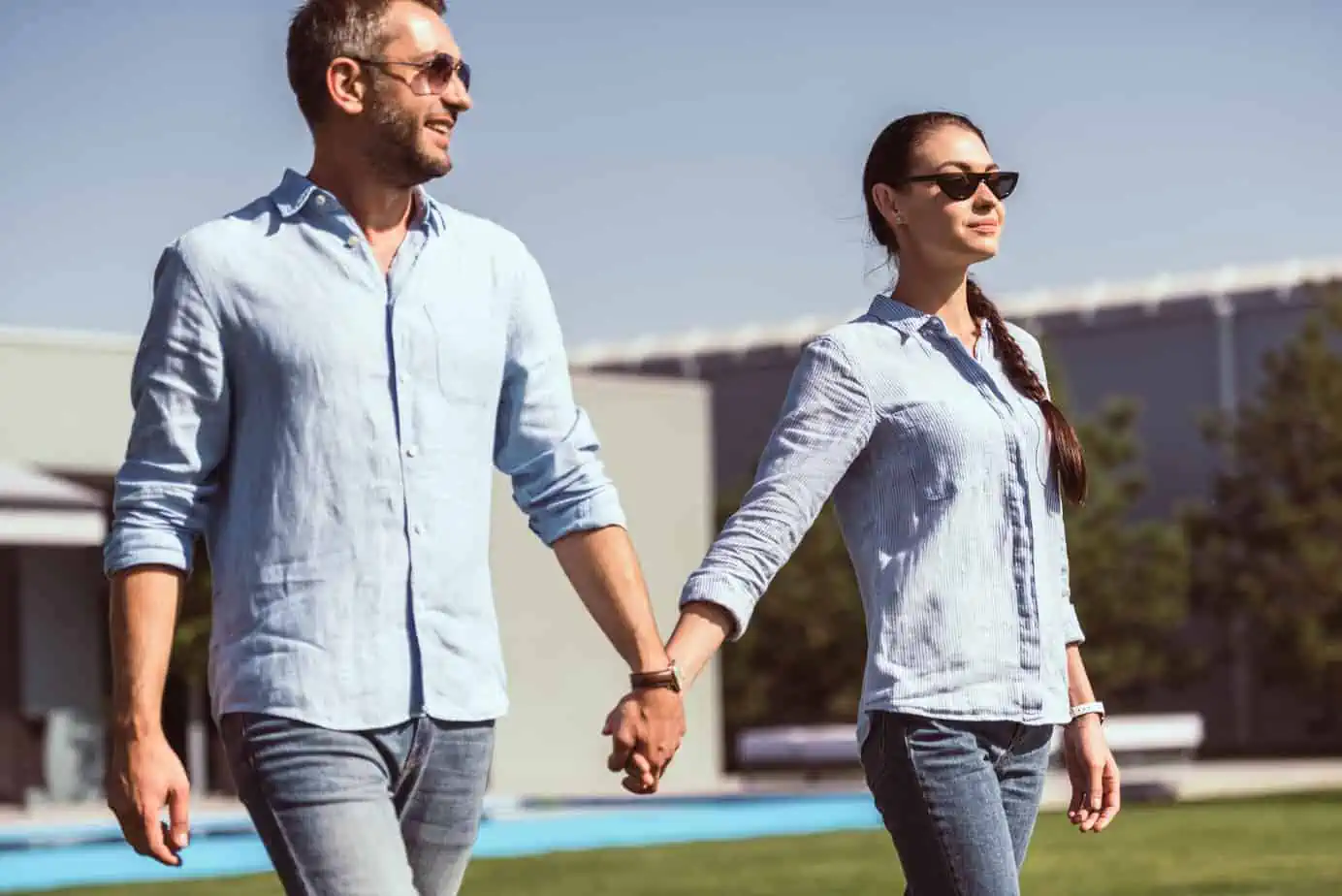 A man and a woman holding hands walking in the grass