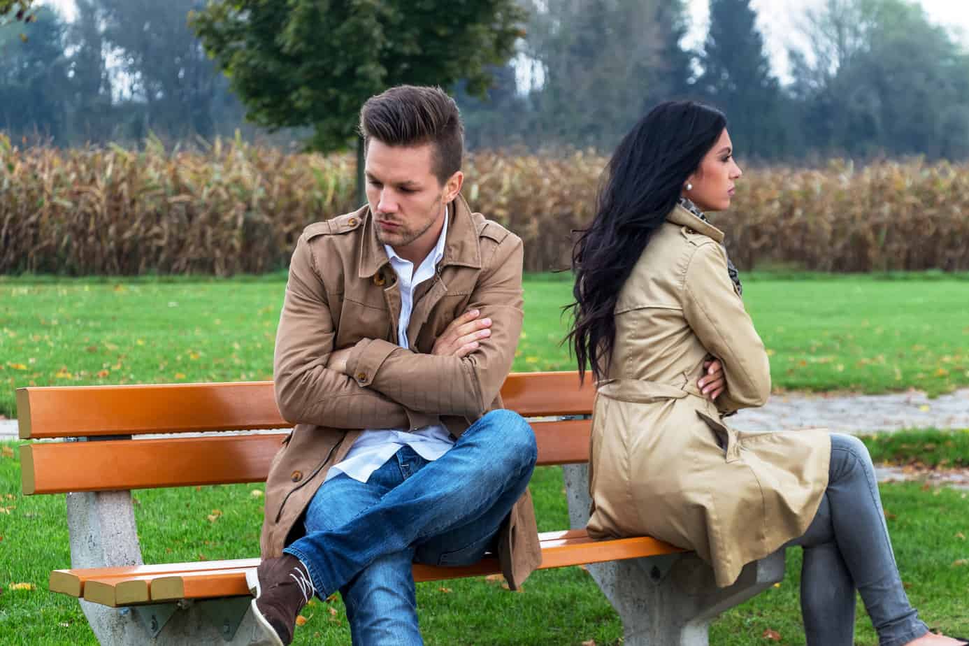 A man and woman sitting on a bench in a park
