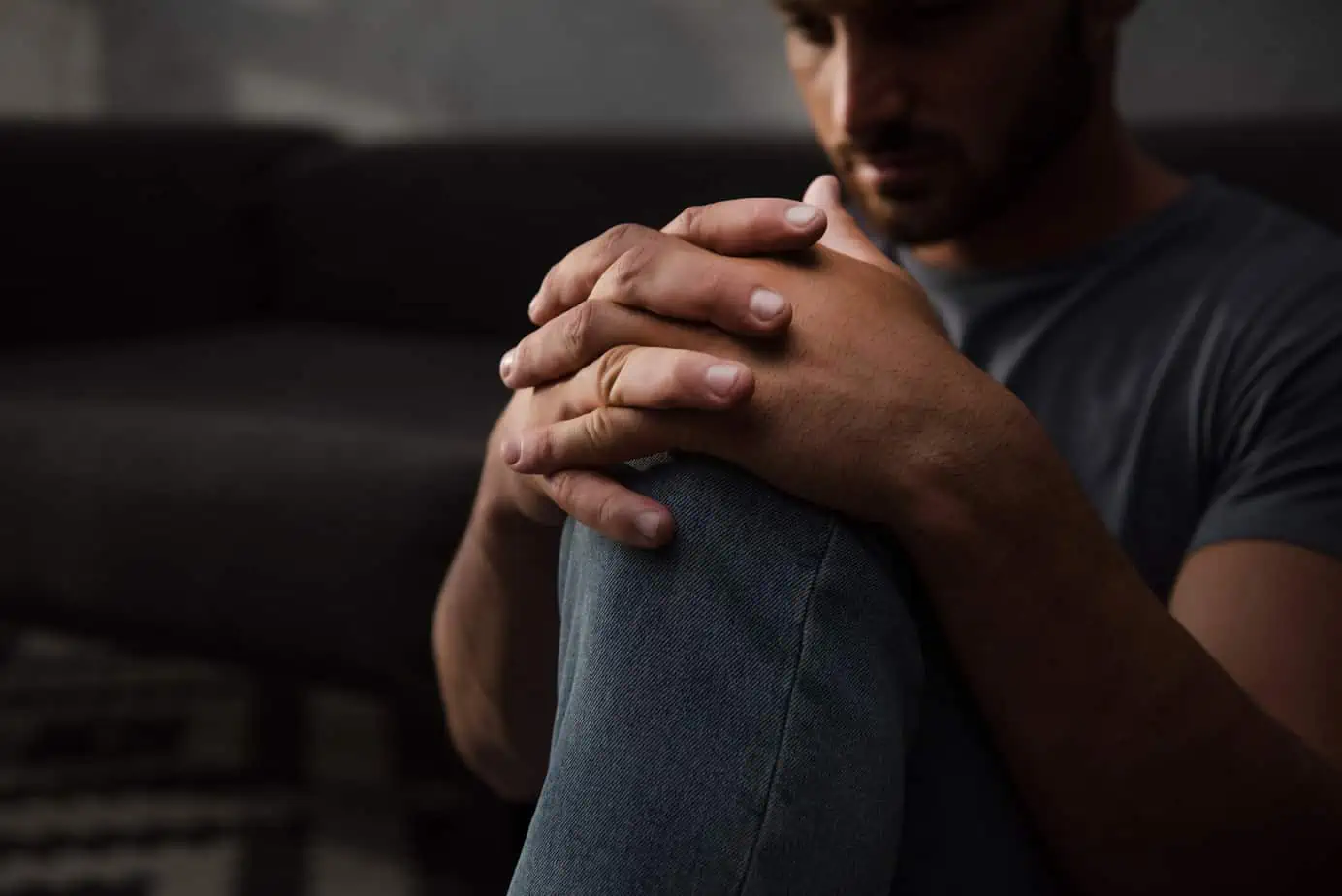 A man sitting on a couch holding his hands together