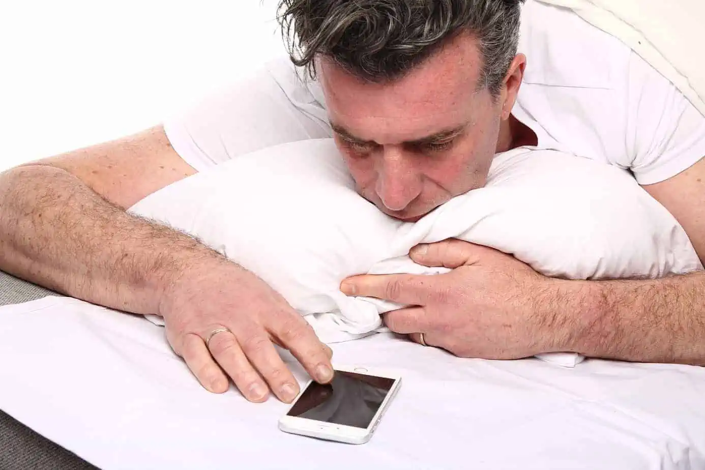 A man laying in bed with a cell phone
