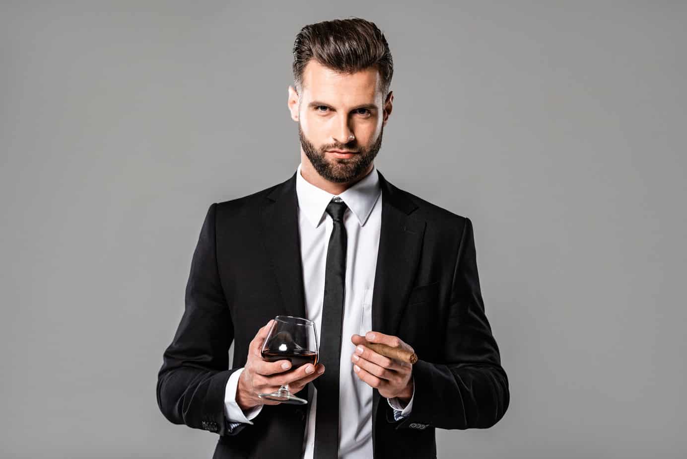 A man in a suit holding a glass of wine