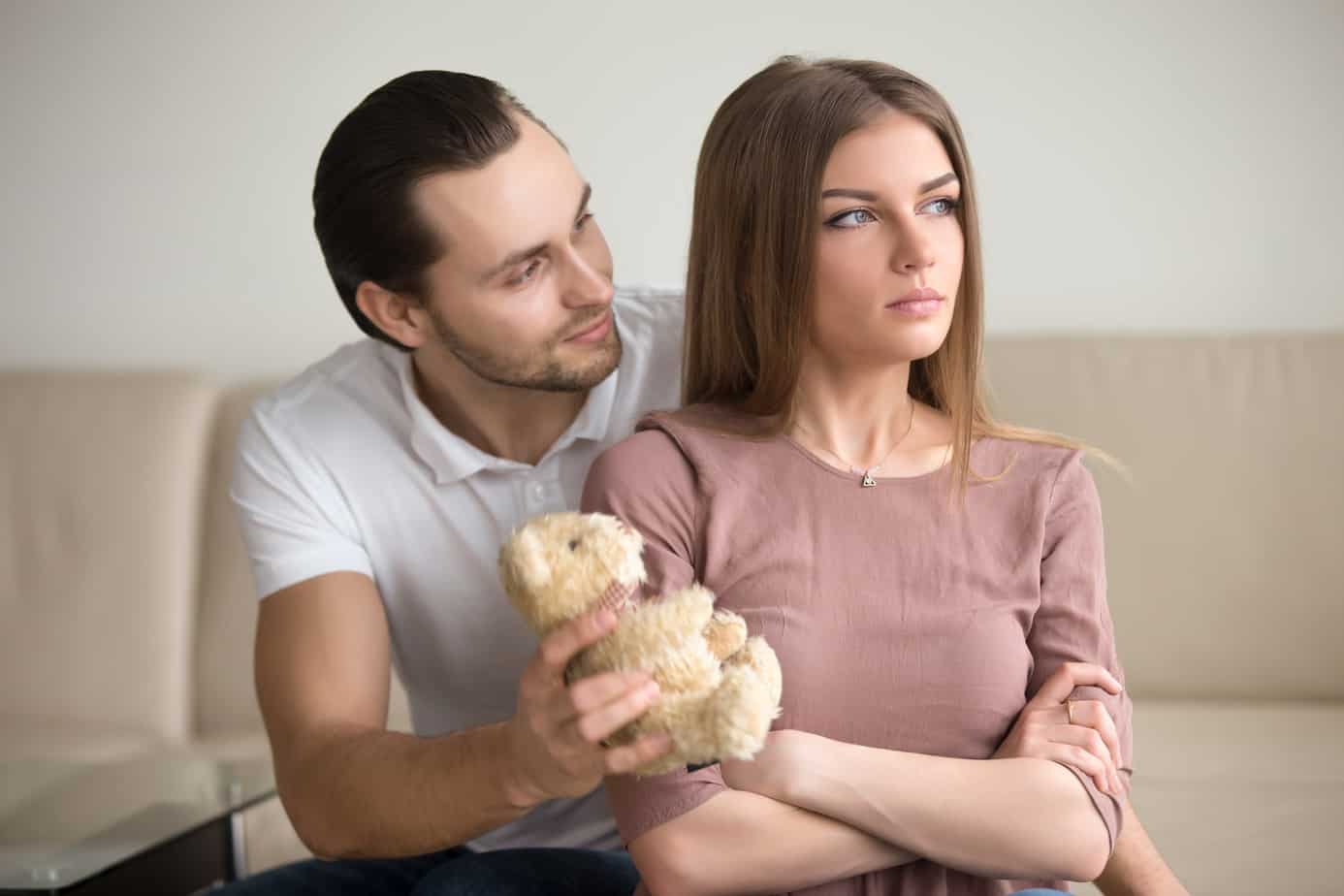 A man holding a teddy bear next to a woman