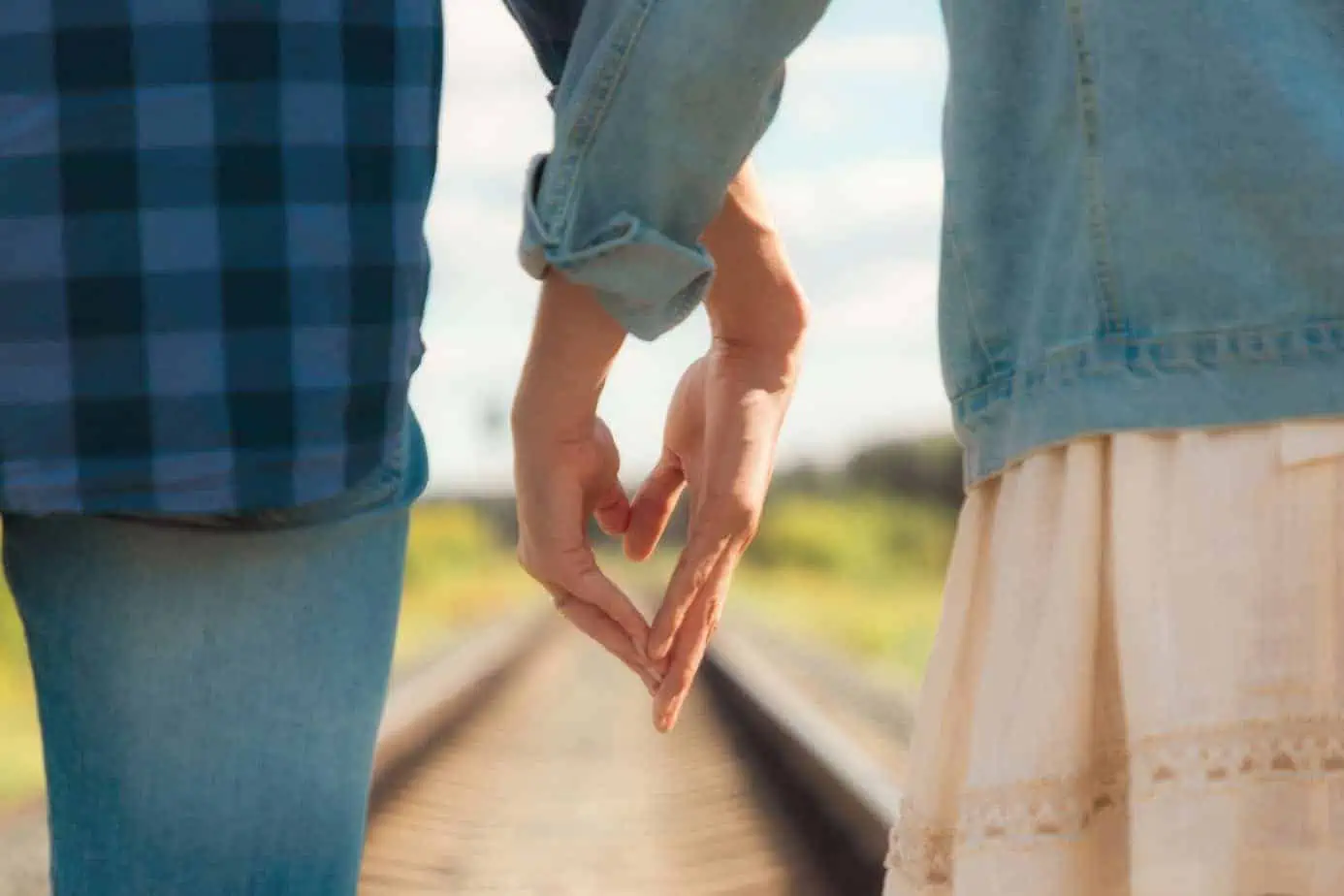 A couple holding hands while walking down a train track
