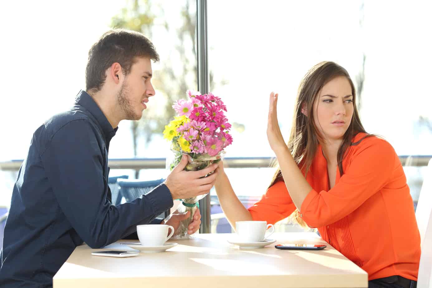 A man giving flowers to a woman at a table