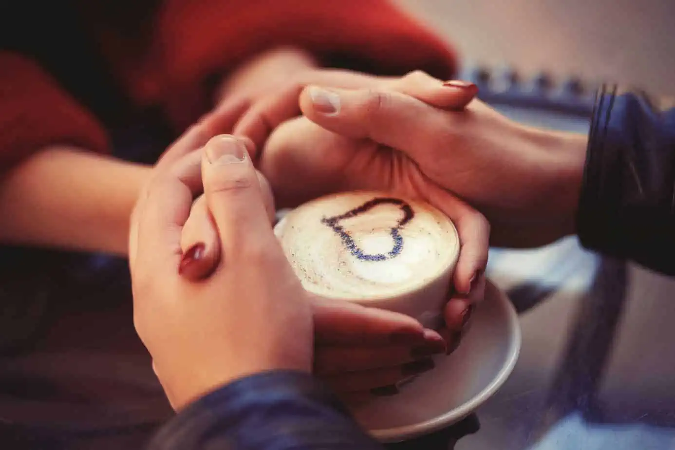Two people holding a coffee cup with a smiley face drawn on it