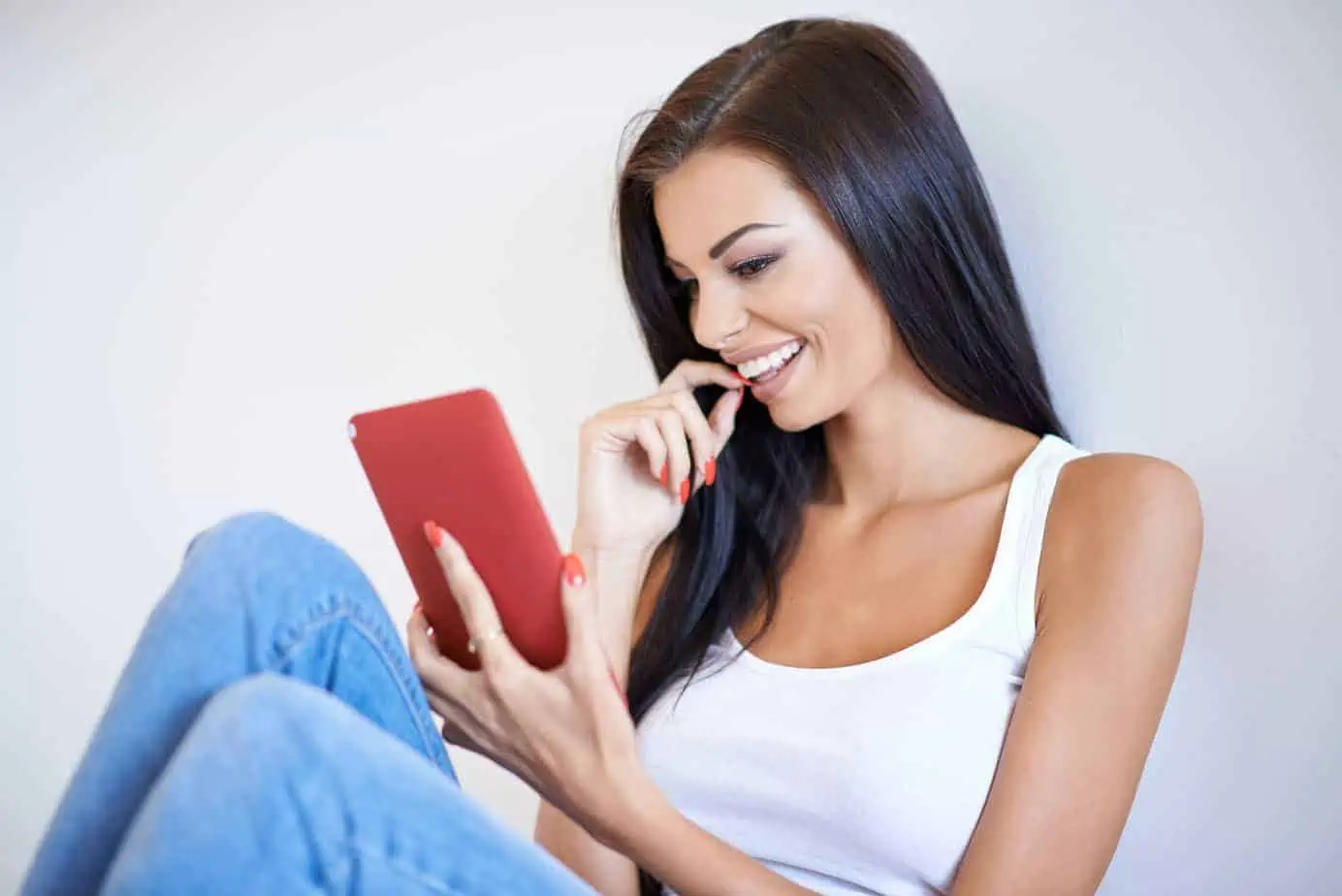A woman is smiling while holding a tablet