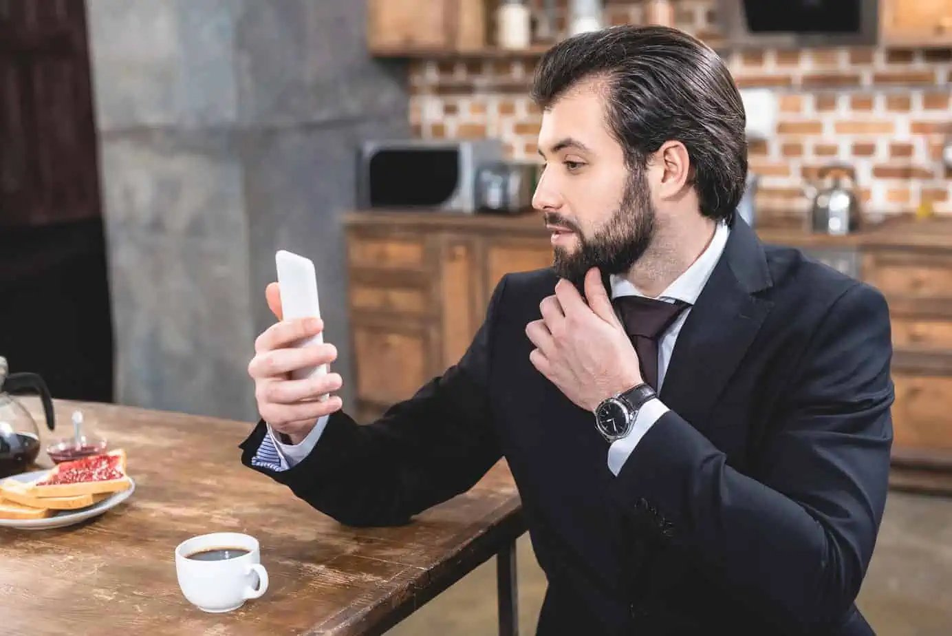 A man in a suit is looking at his cell phone