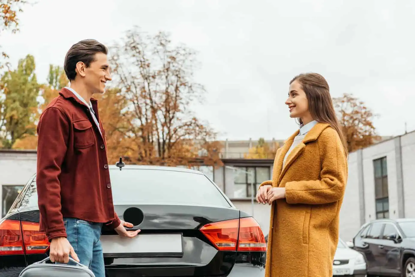 A man and a woman standing next to a car