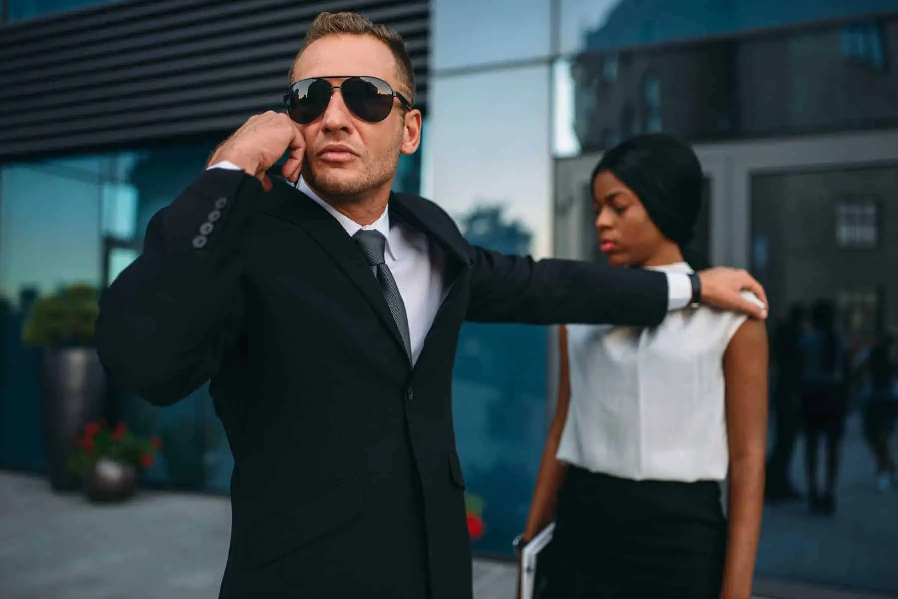 A man in a suit and sunglasses talking on a cell phone