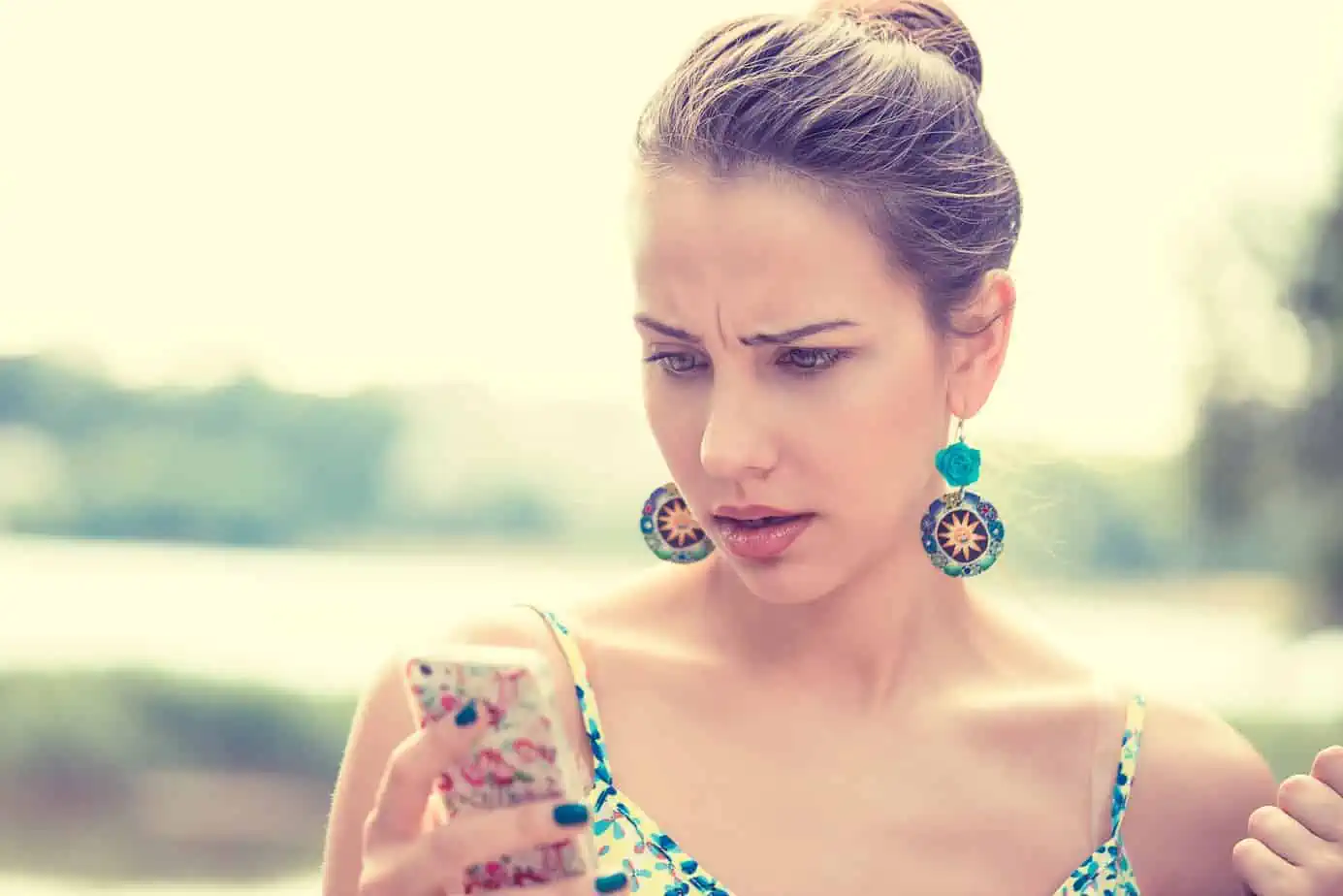 A woman looking at her cell phone while wearing earrings
