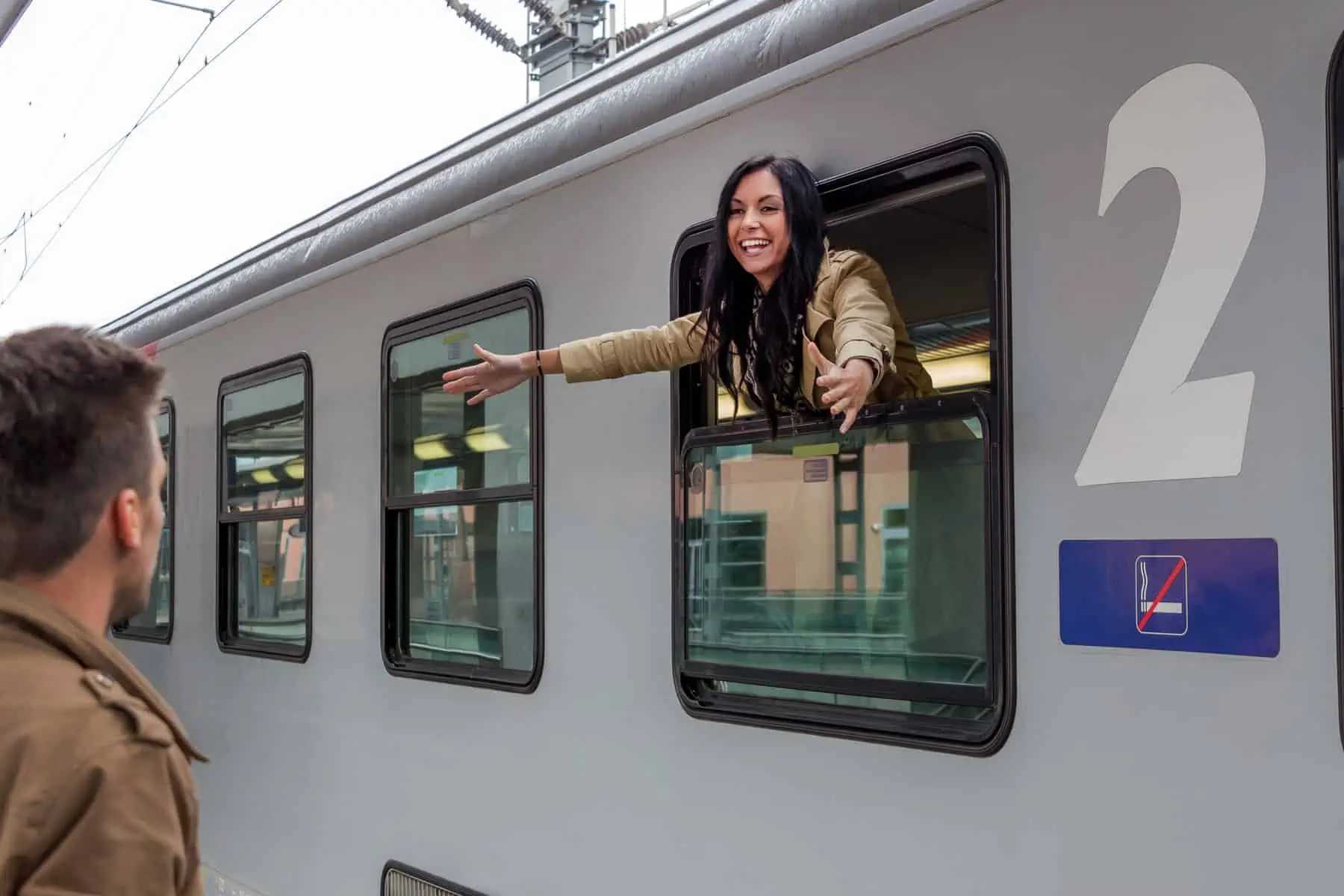 A woman is waving out the window of a train