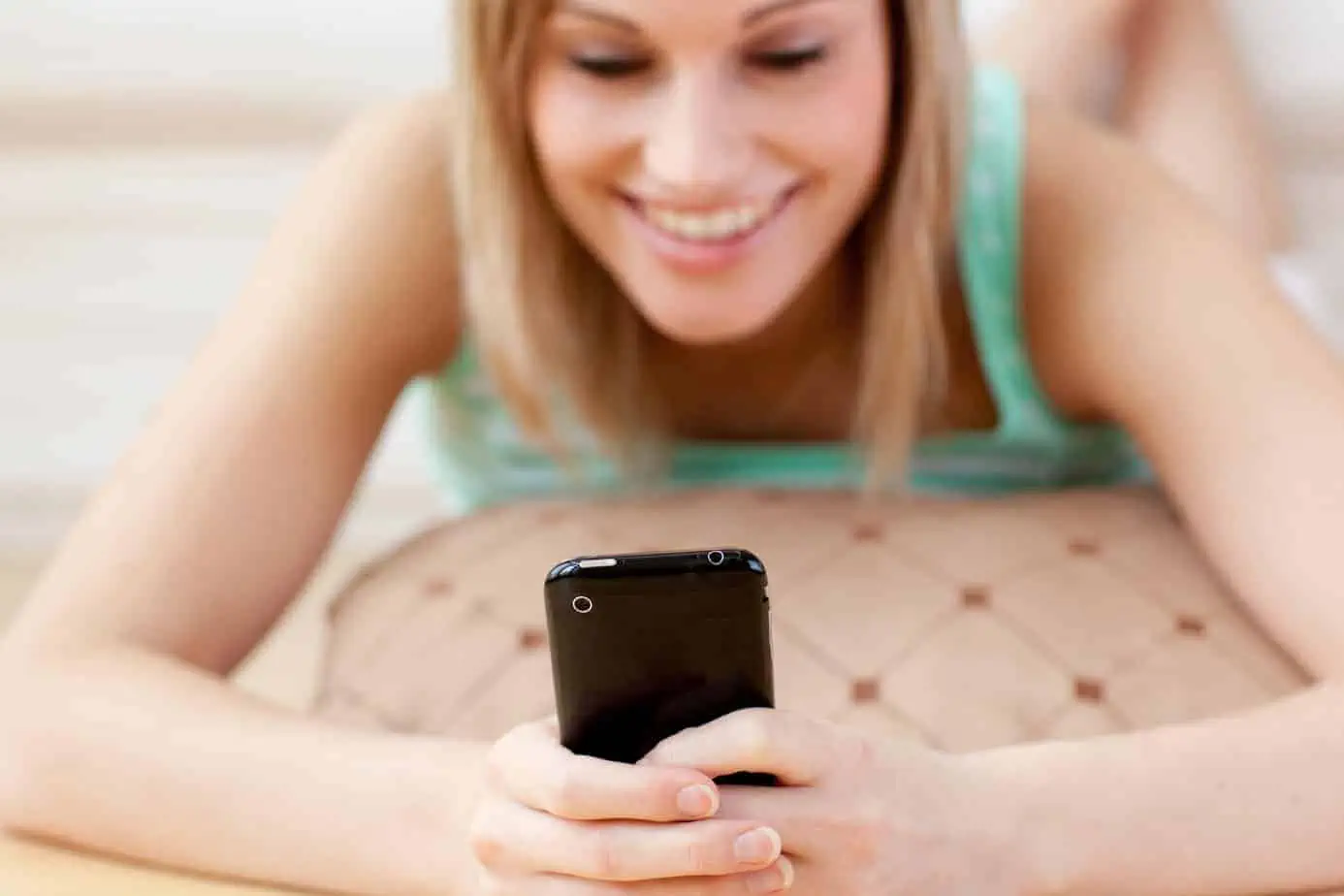A woman is smiling while looking at her cell phone