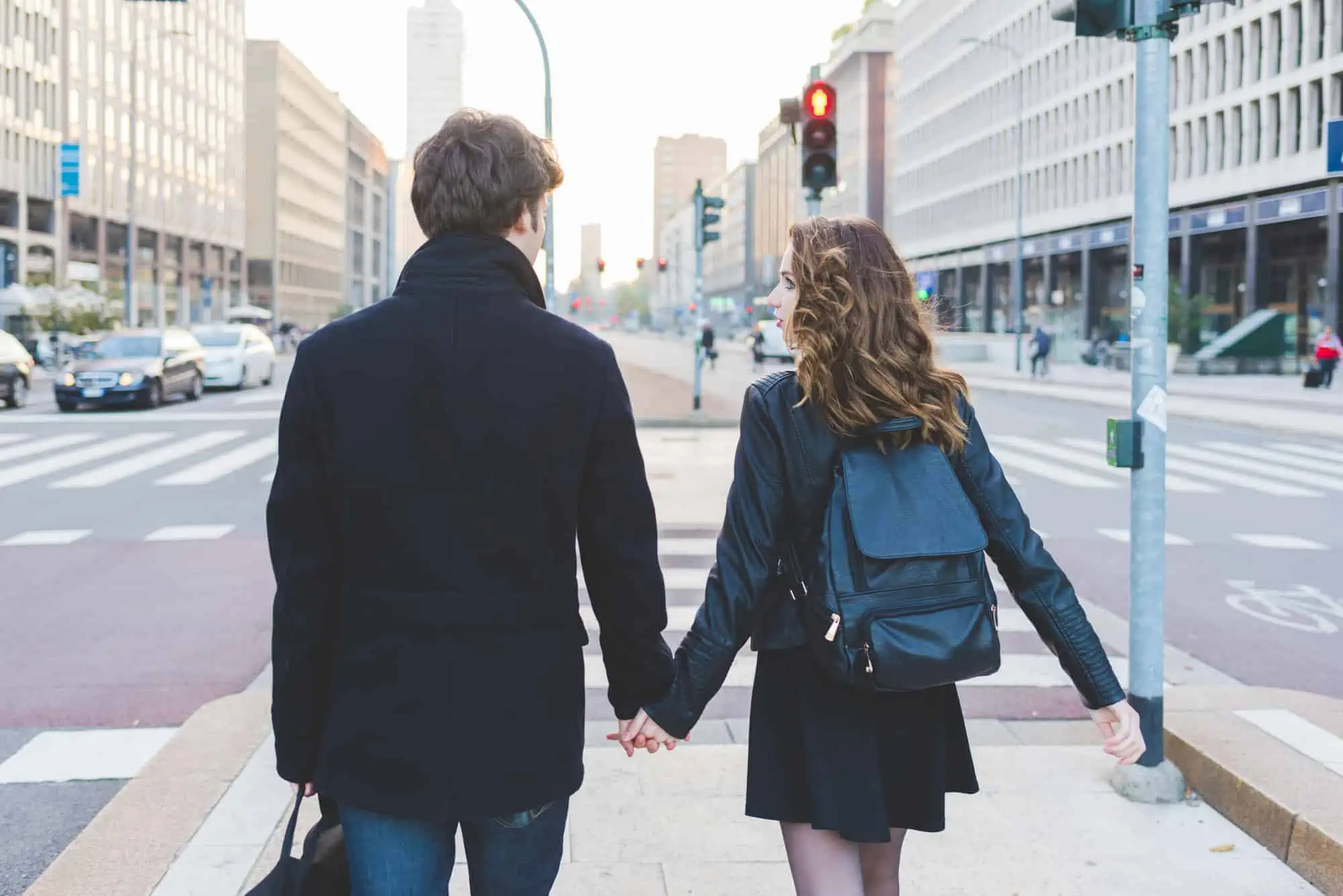 A man and a woman walking down a street holding hands