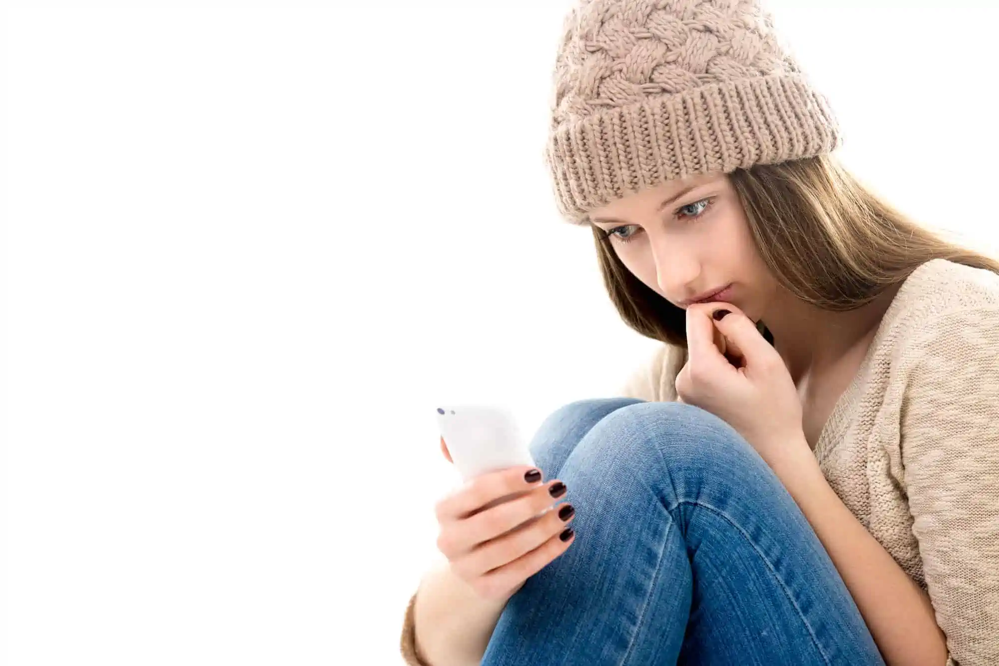 A woman sitting on the floor looking at her cell phone