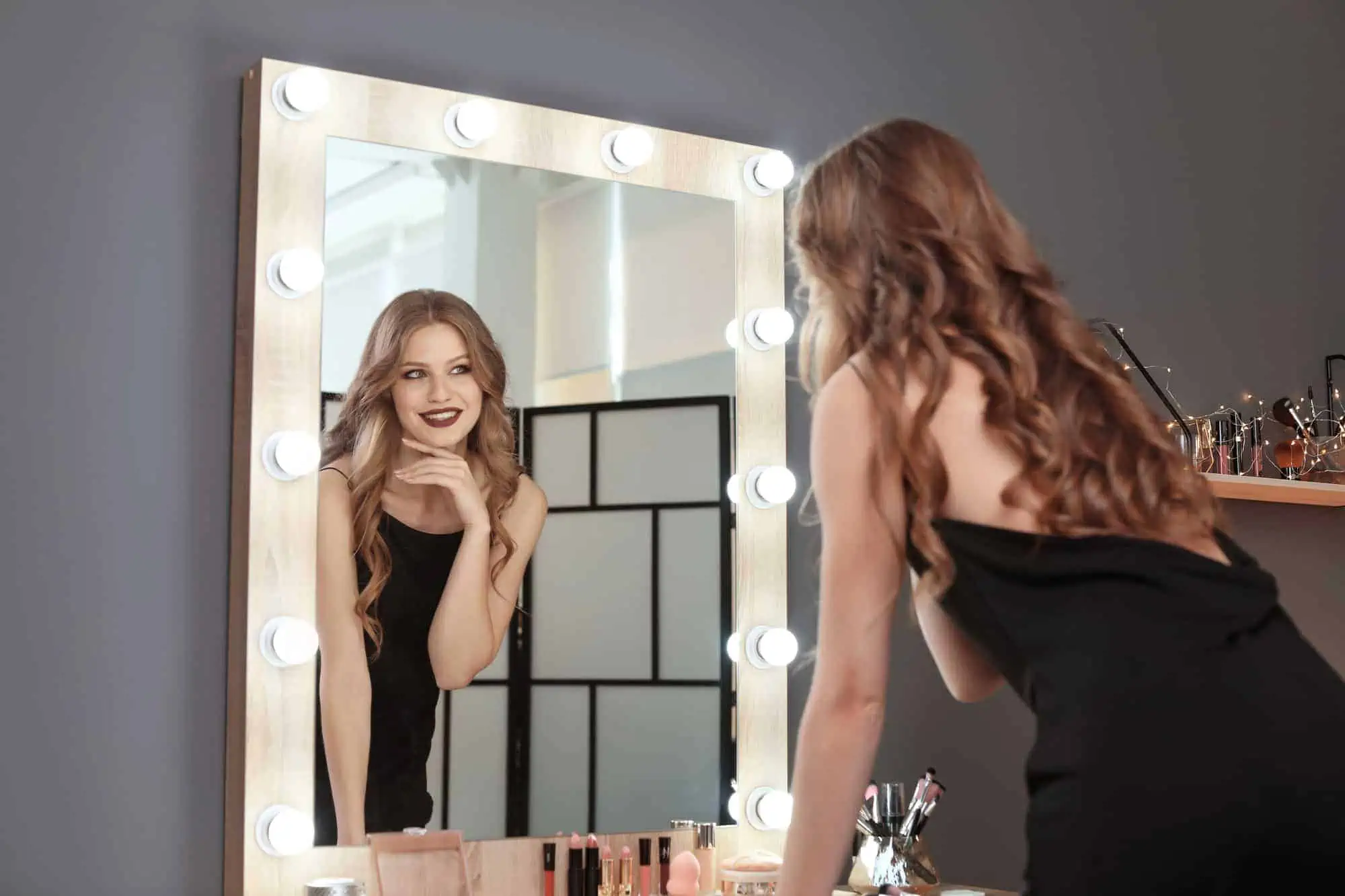 A woman standing in front of a mirror looking at herself in the mirror
