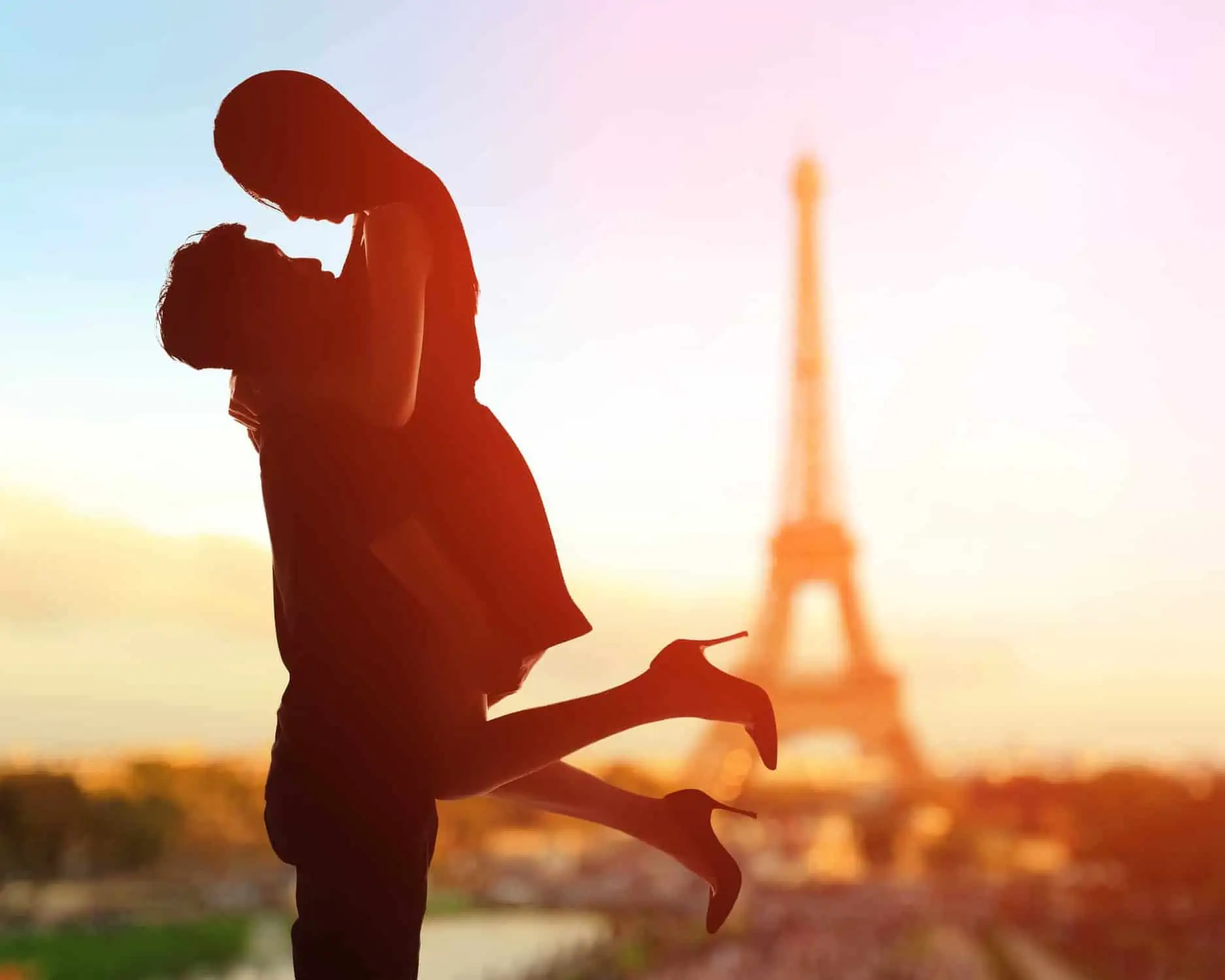 A couple kissing in front of the eiffel tower