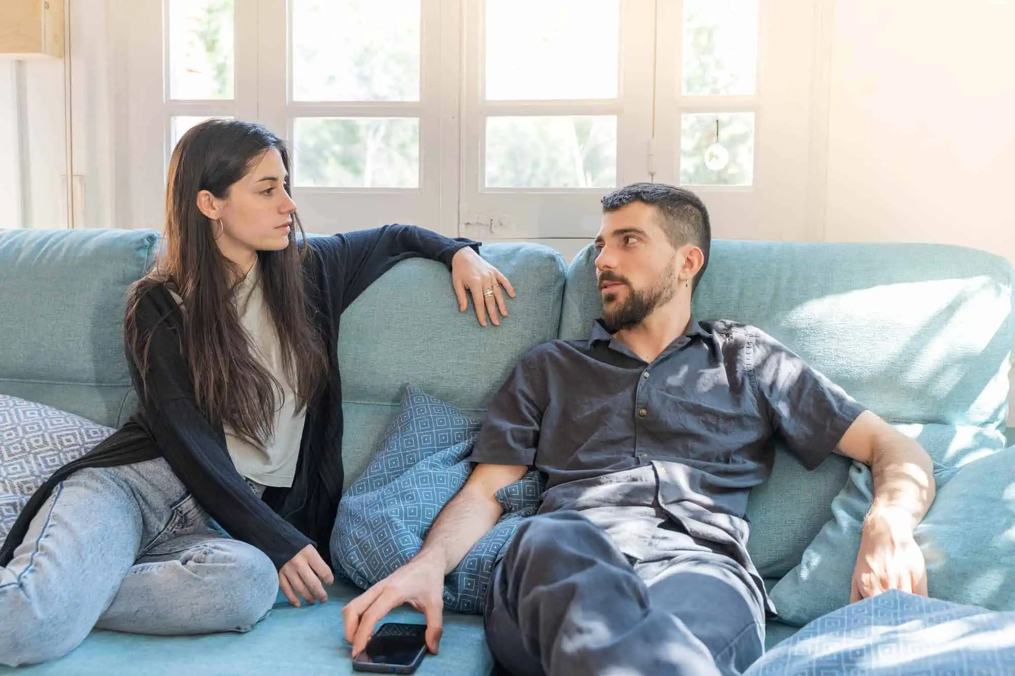 A man and a woman sitting on a couch looking at each other