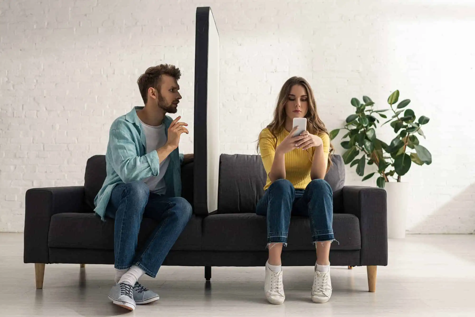 A man and woman sitting on a couch looking at their phones