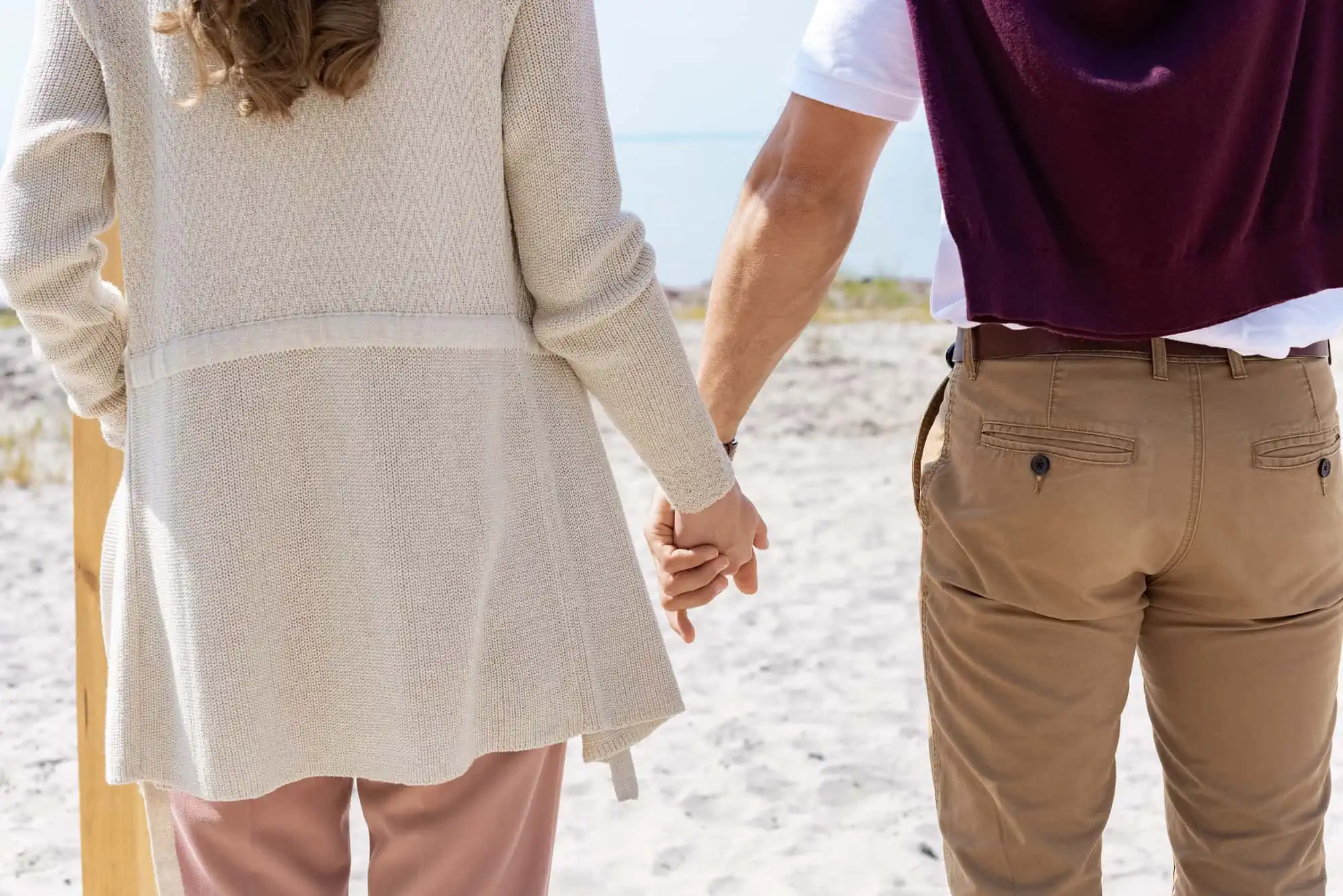 A man and a woman holding hands on a beach