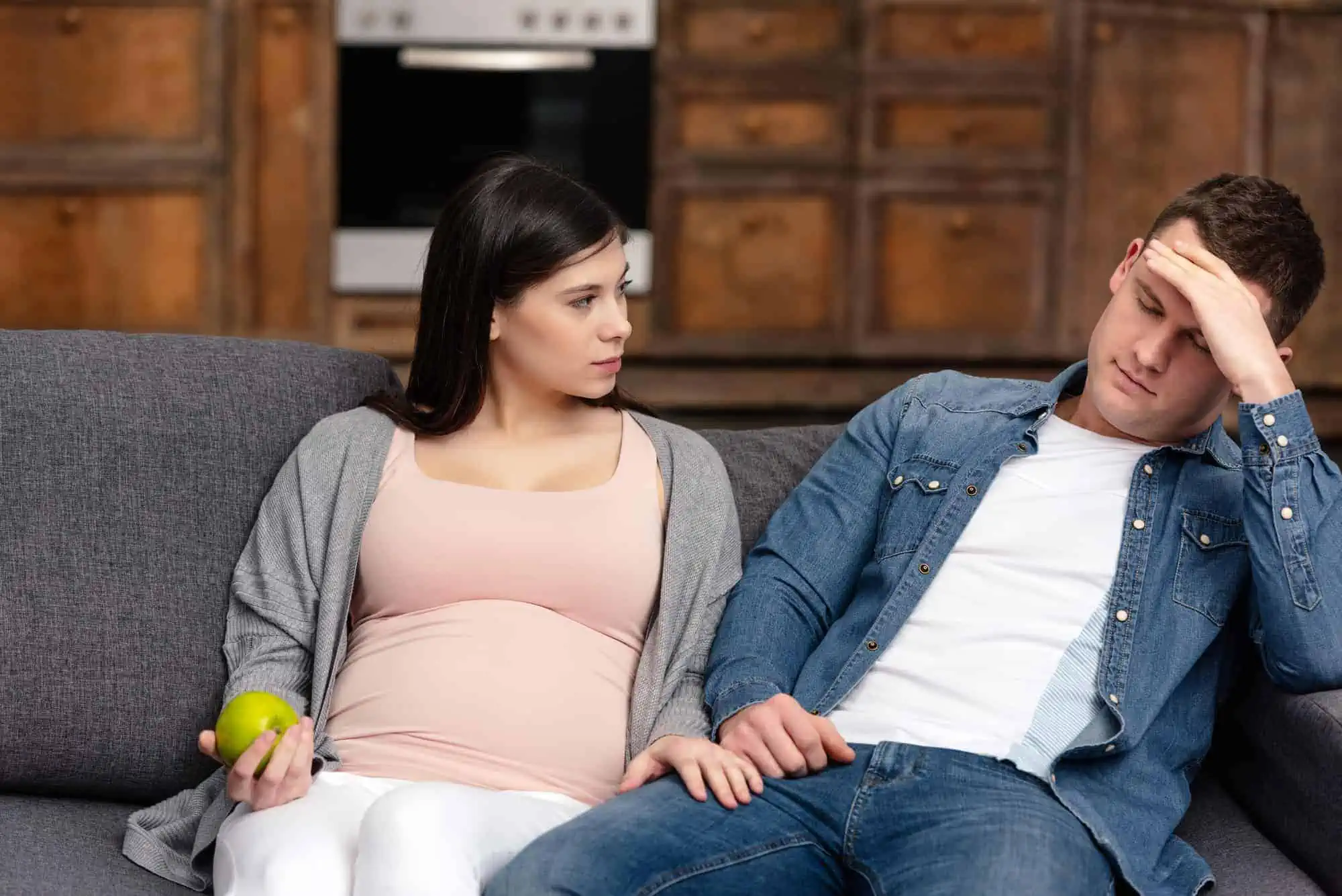 A pregnant woman sitting on a couch next to a man