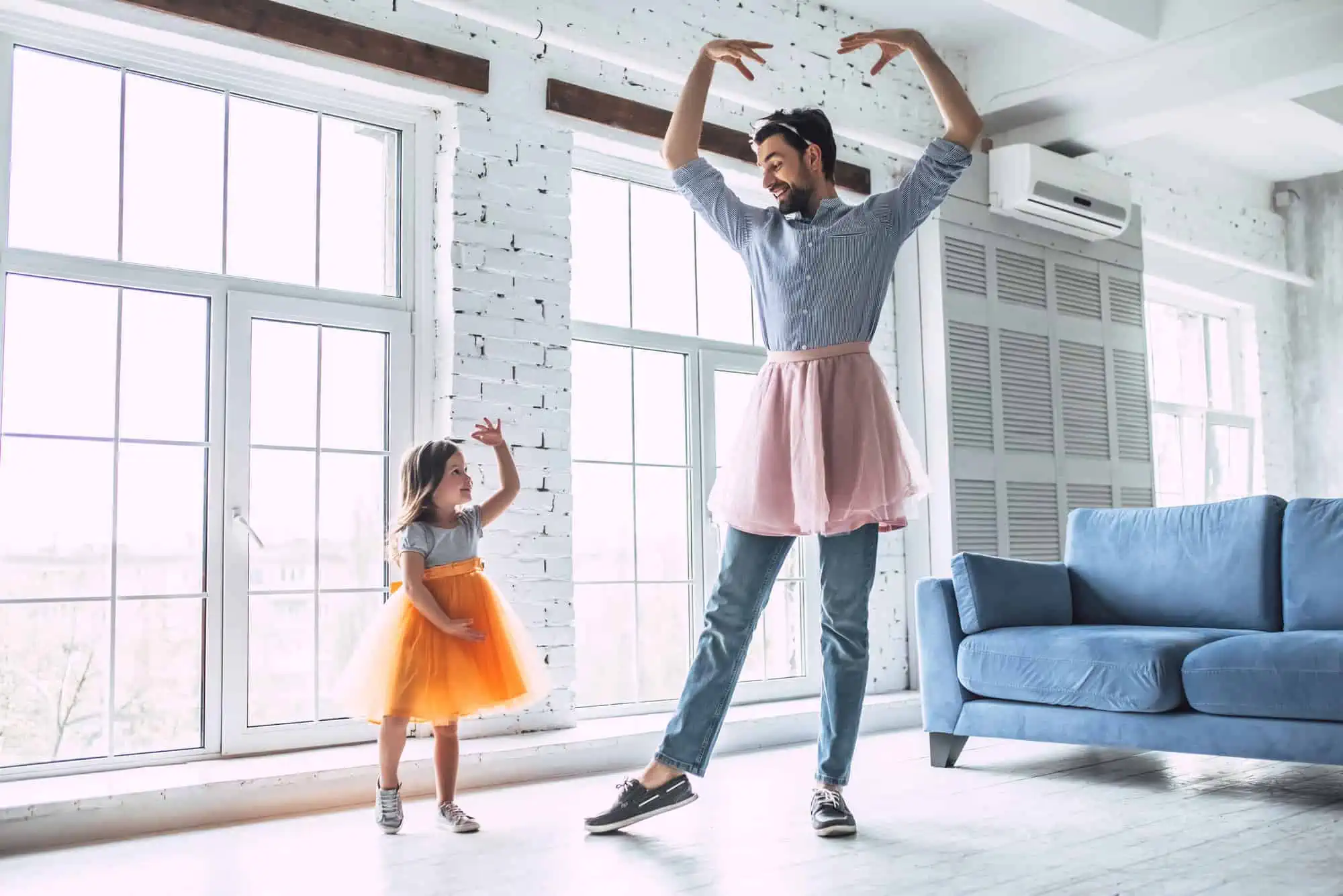 A man and a little girl dancing in a living room