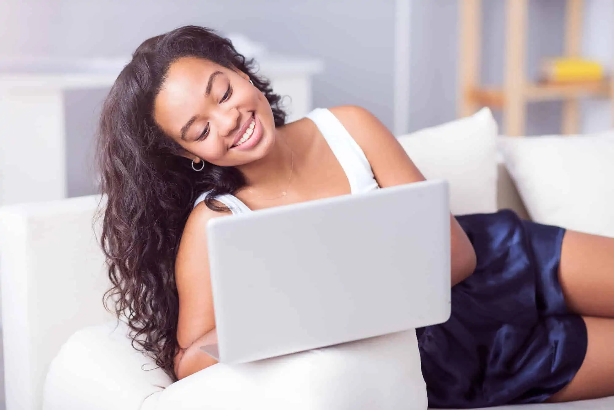 A woman laying on a couch using a laptop
