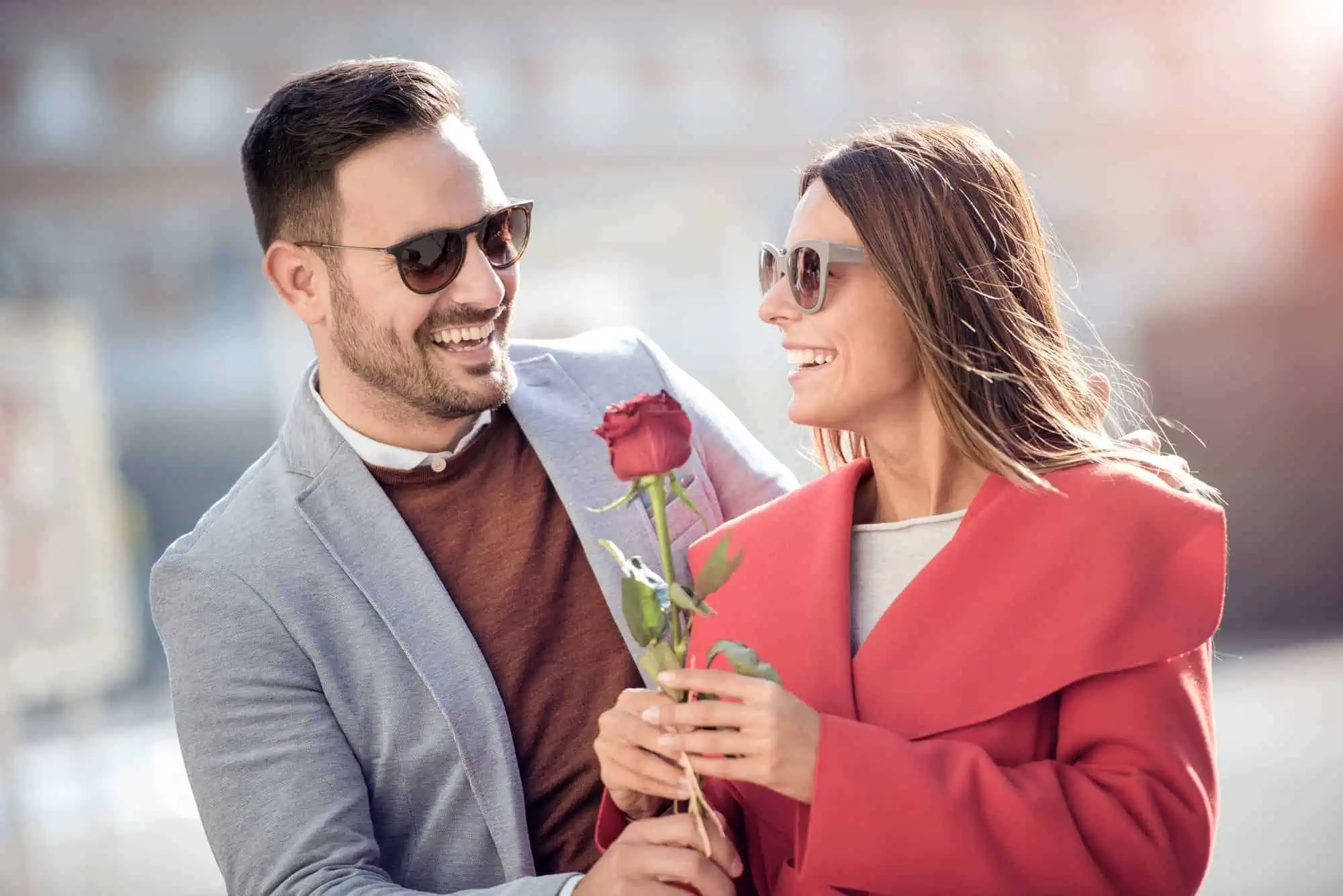 A man holding a rose and smiling at a woman