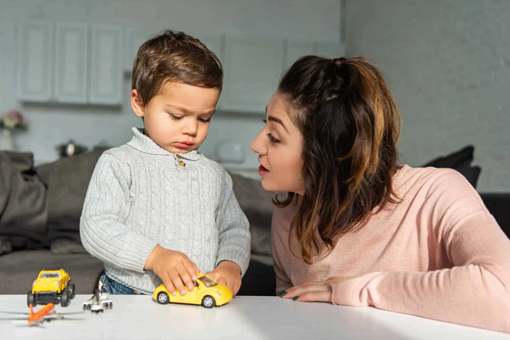 A woman and a child playing with a toy car
