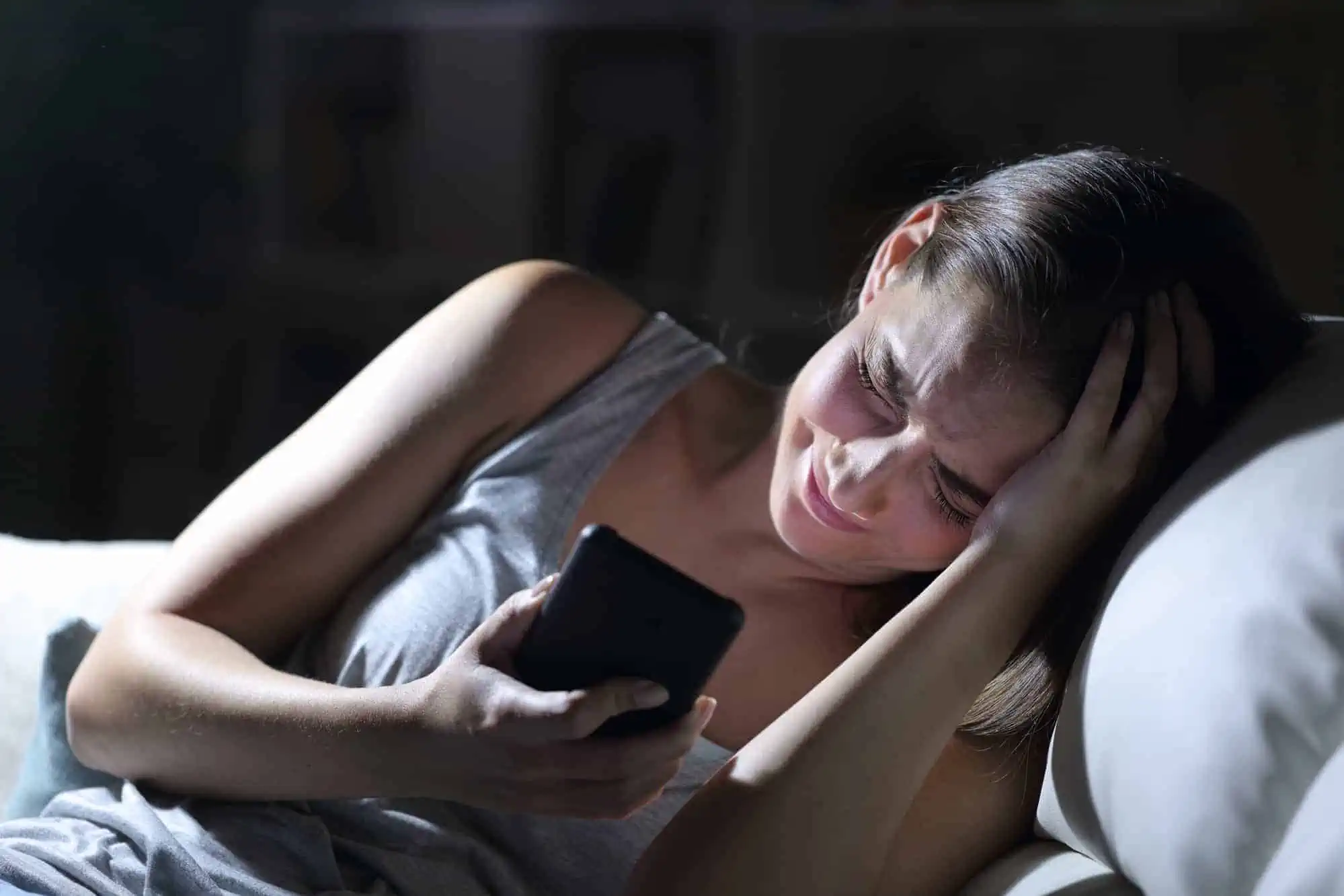 A woman laying on a couch holding a cell phone