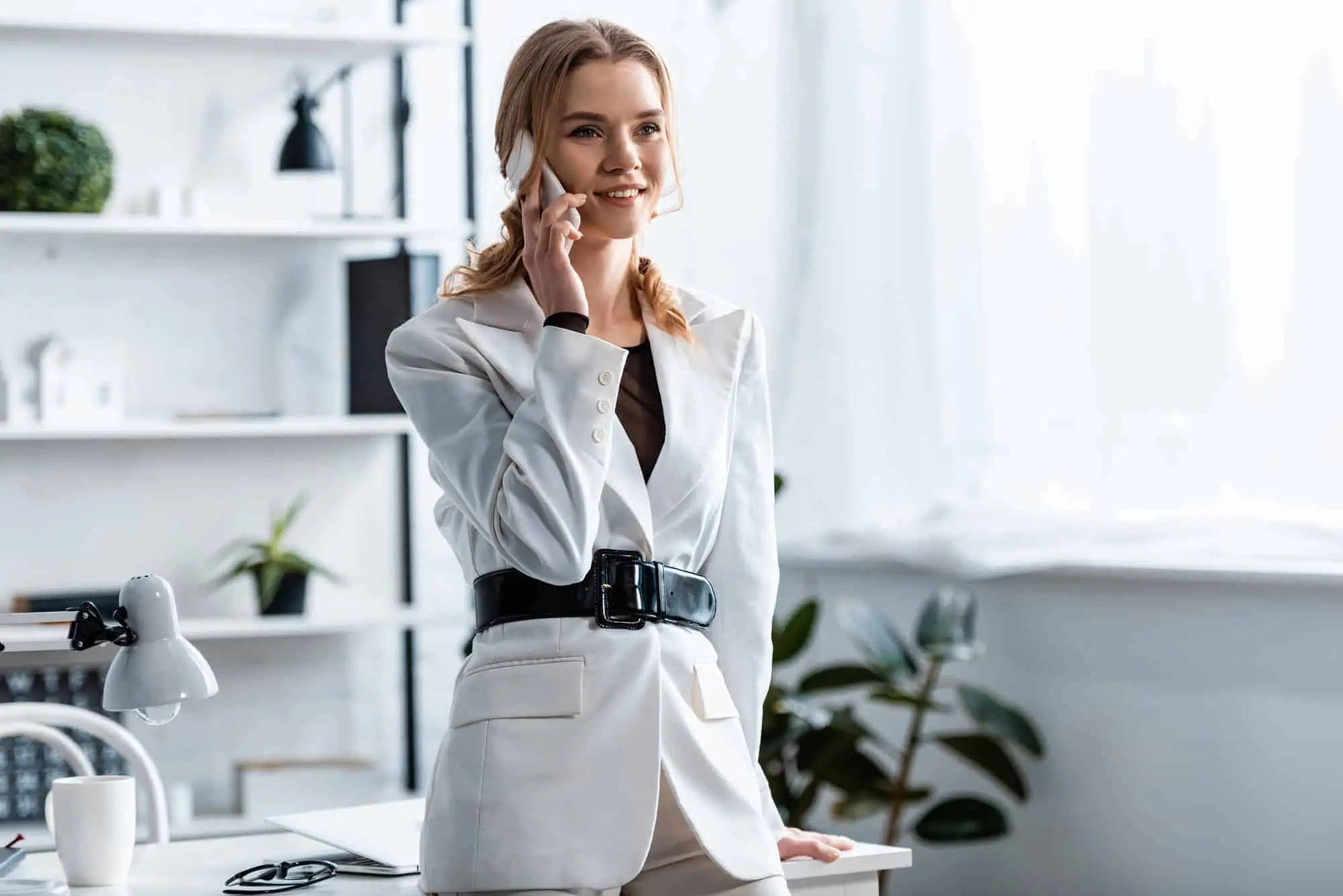 A woman in a white suit talking on a cell phone