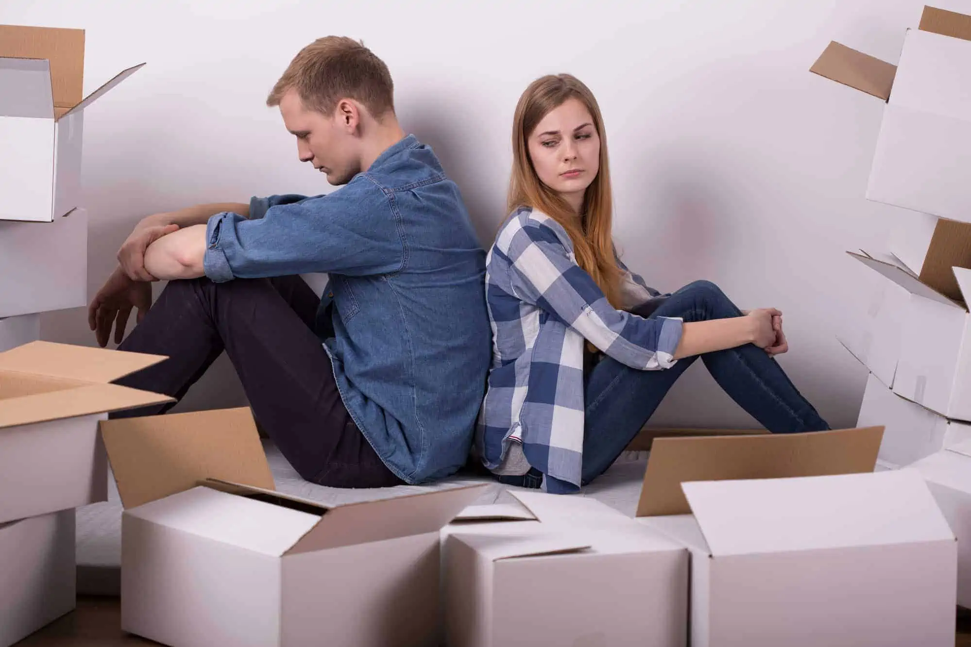 A man and a woman sitting on cardboard boxes