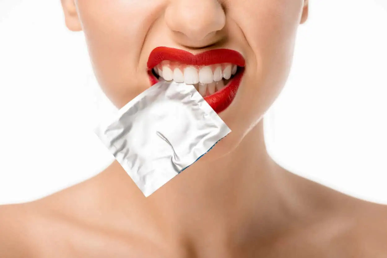 Girl biting on a packet of condom