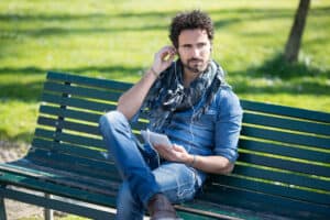Man sitting on a park bench listening to music