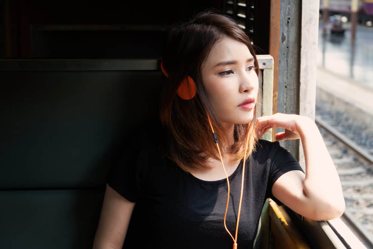 Sad woman in train wearing headphones
